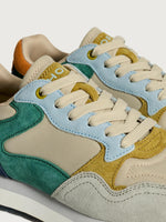 Colorful sneakers with a mix of beige, blue, green, and yellow on a light gray background